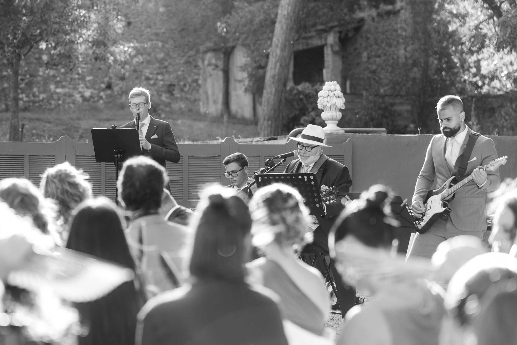 Guests seated at the ceremony, with a musician playing, in black and white