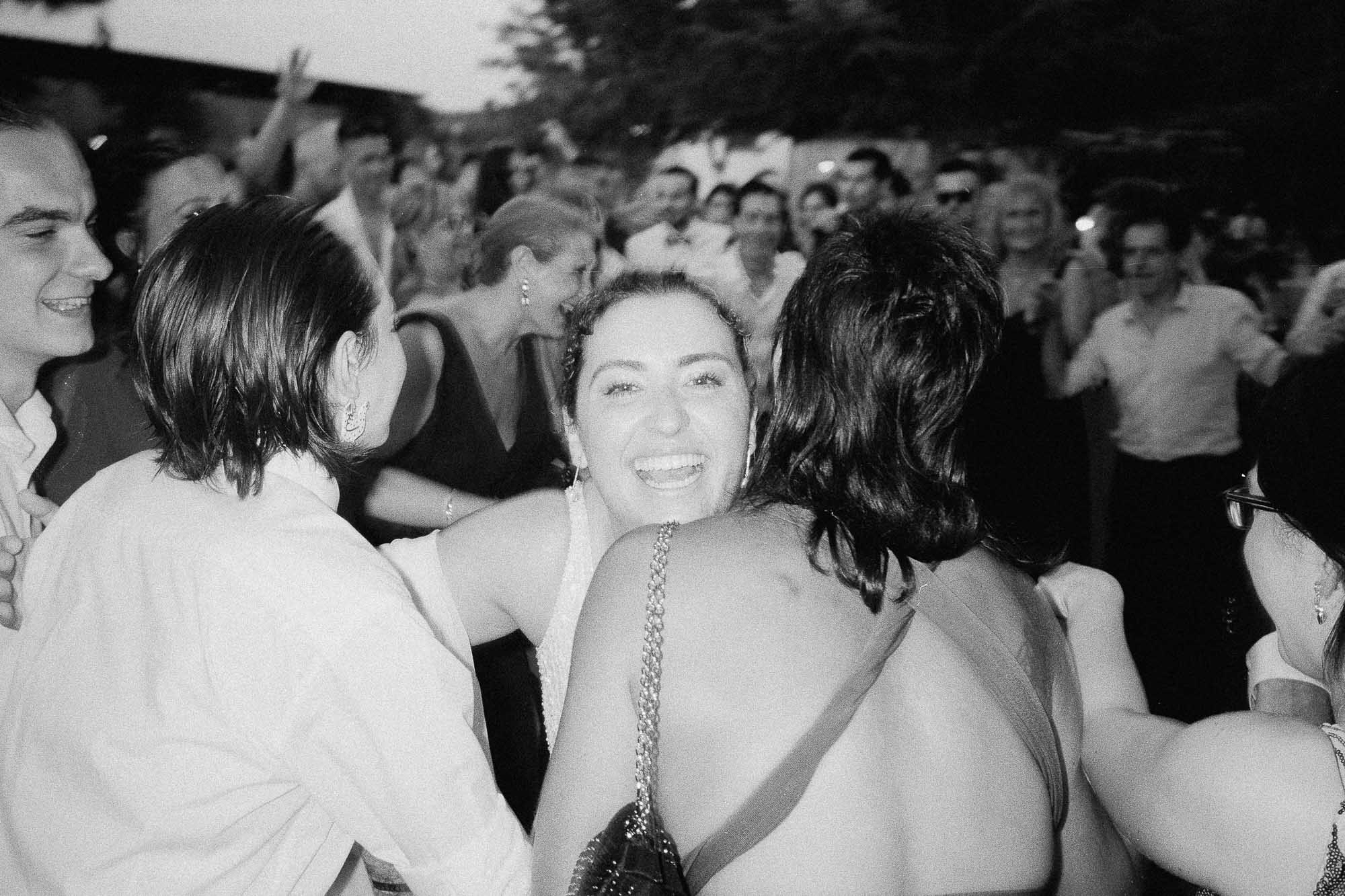 Fotografia en blanc i negre d’una munió de convidats ballant molt junts, amb una dona somrient a la càmera