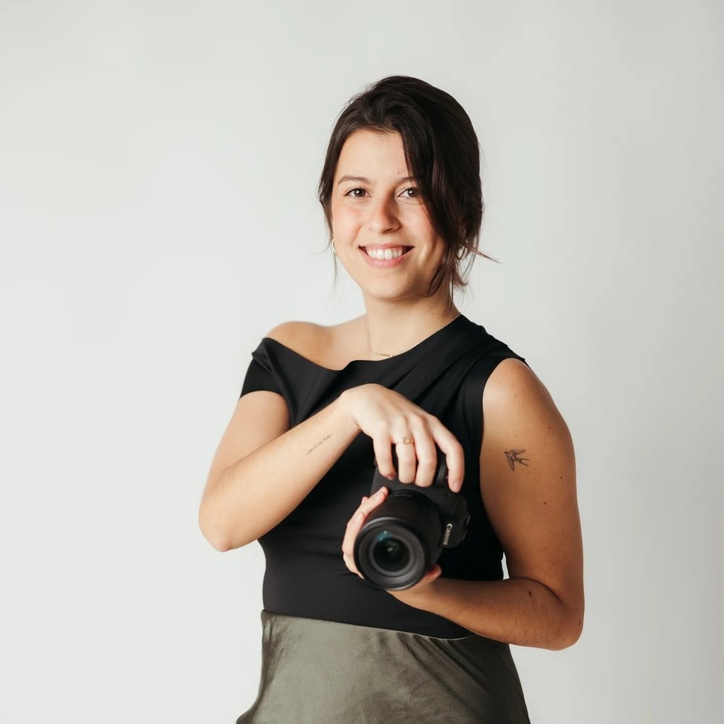 Photographer smiling and holding a camera, Timeless Wedding Studio