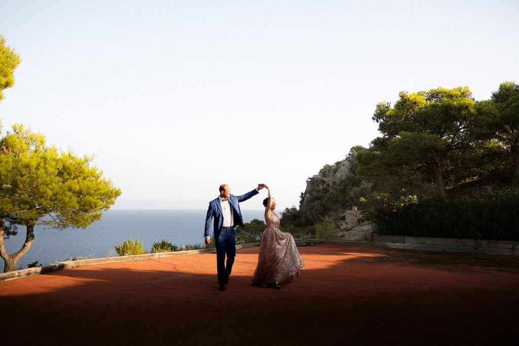 Couple dancing on a terrace above the Mediterranean sea at a wedding in Spain, wide view