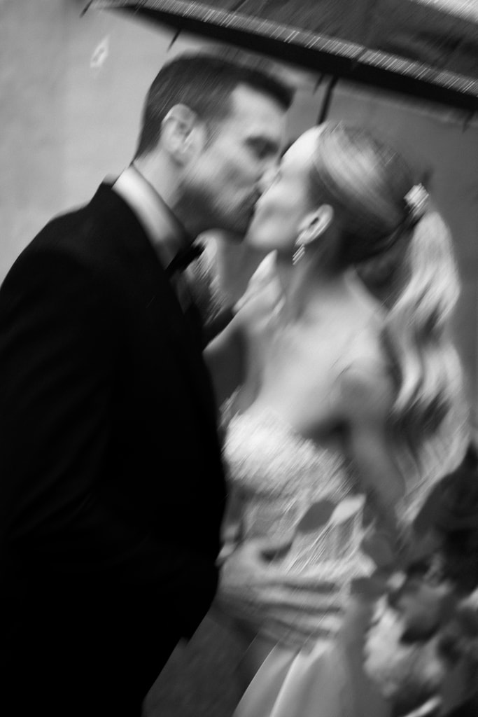 Black and white shot of the couple kissing with motion blur, the groom in a dark suit, wedding photography in Catalonia