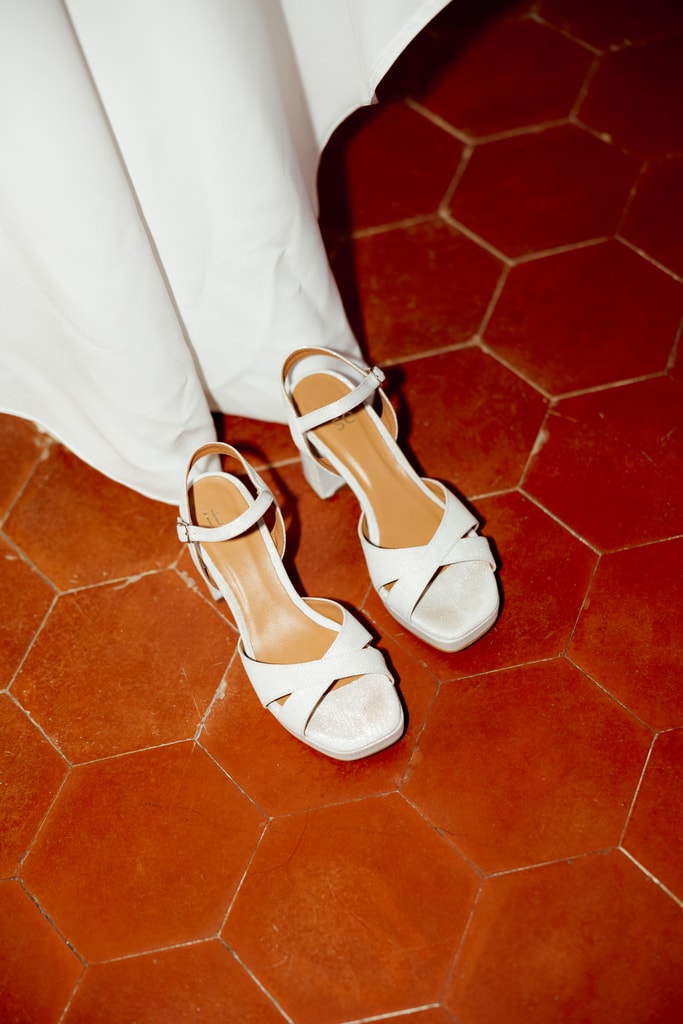 White bridal sandals and dress hem on bright red hexagonal tiles, wedding photography in Catalonia