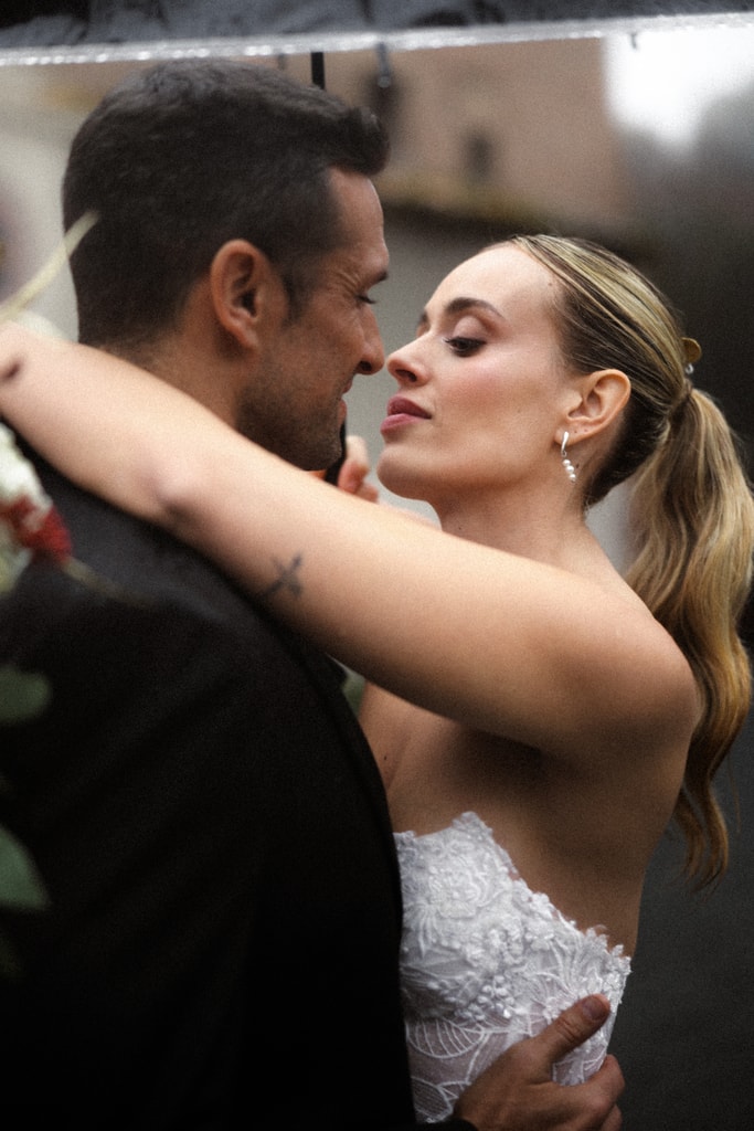 Close embrace of the couple, the bride in lace with her hair tied back, the groom in a dark suit, faces close, wedding photography in Catalonia